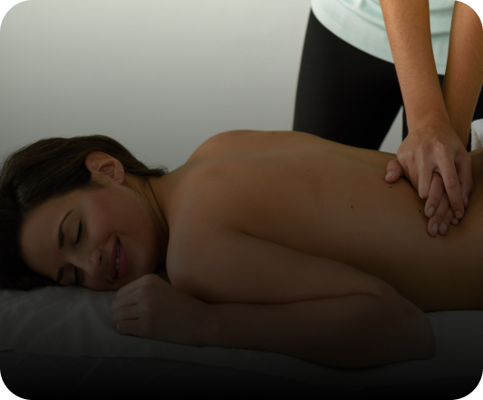 Una mujer disfrutando de un masaje relajante, mientras un terapeuta aplica una suave presión en la espalda y los hombros.